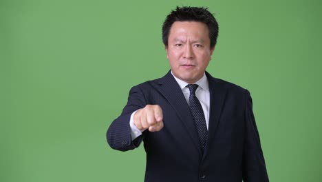 Mature-Japanese-businessman-against-green-background