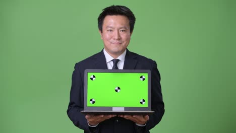 Mature-Japanese-businessman-against-green-background