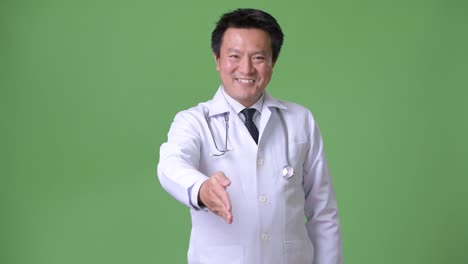 Mature-Japanese-man-doctor-against-green-background