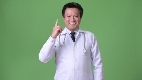 Mature-Japanese-man-doctor-against-green-background