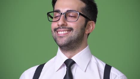 Young-handsome-bearded-Persian-businessman-against-green-background