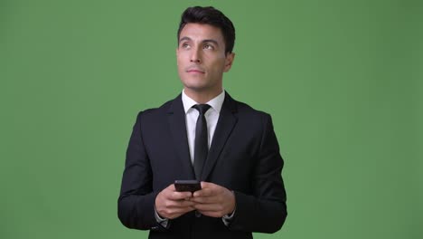 Young-handsome-Hispanic-businessman-against-green-background