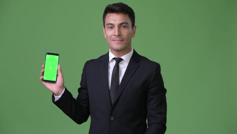 Young-handsome-Hispanic-businessman-against-green-background