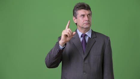 Mature-handsome-businessman-against-green-background