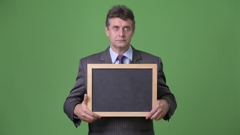 Mature-handsome-businessman-against-green-background