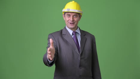 Mature-handsome-businessman-against-green-background