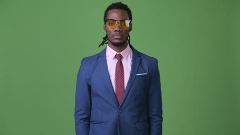 Young-handsome-African-businessman-with-dreadlocks-against-green-background