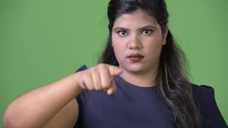 Young-overweight-beautiful-Indian-businesswoman-against-green-background