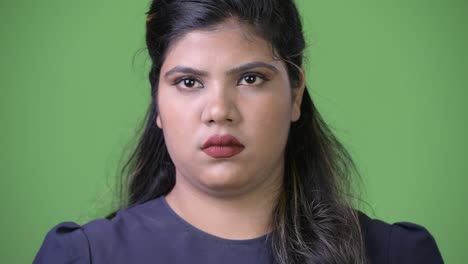 Young-overweight-beautiful-Indian-businesswoman-against-green-background