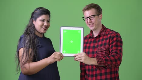 Young-multi-ethnic-business-couple-together-against-green-background