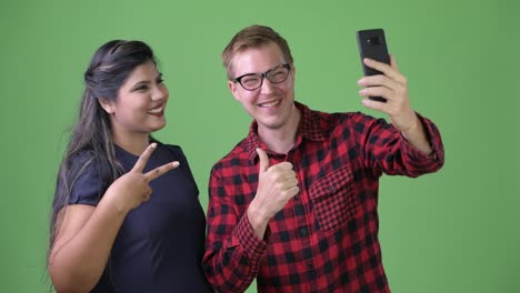 Young-multi-ethnic-business-couple-together-against-green-background