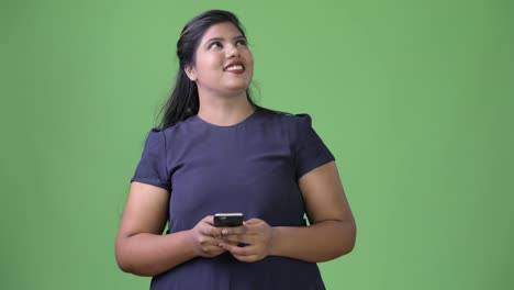 Young-overweight-beautiful-Indian-businesswoman-against-green-background