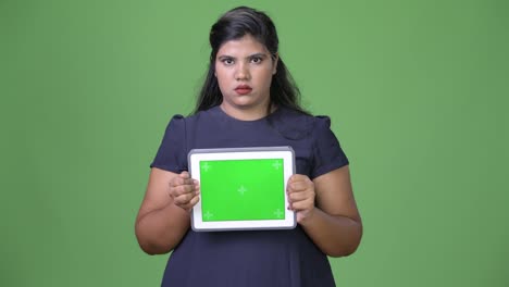 Young-overweight-beautiful-Indian-businesswoman-against-green-background