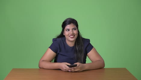 Young-overweight-beautiful-Indian-businesswoman-against-green-background