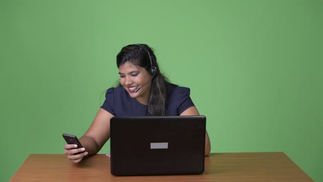 Young-overweight-beautiful-Indian-businesswoman-against-green-background