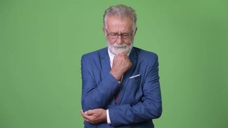 Handsome-senior-bearded-businessman-against-green-background