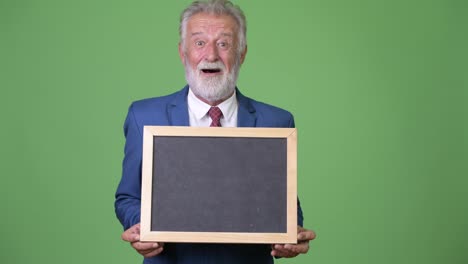 Handsome-senior-bearded-businessman-against-green-background