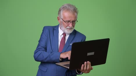 Handsome-senior-bearded-businessman-against-green-background