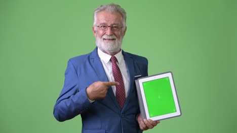 Handsome-senior-bearded-businessman-against-green-background