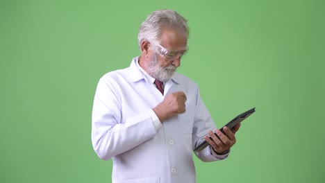 Handsome-senior-bearded-man-doctor-against-green-background