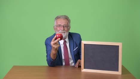 Gut-aussehend-senior-bärtigen-Geschäftsmann-vor-grünem-Hintergrund