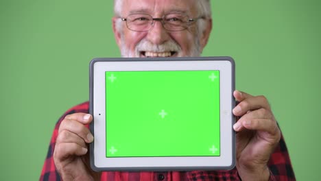 Gut-aussehend-Senior-bärtiger-Mann-vor-grünem-Hintergrund