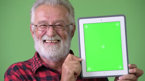 Handsome-senior-bearded-man-against-green-background