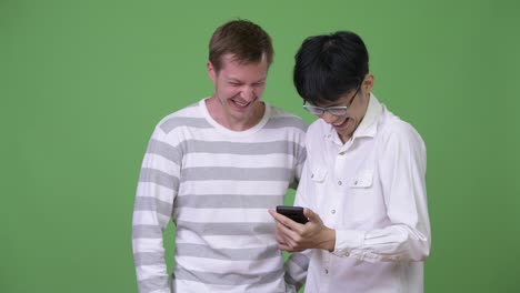 Two-happy-young-multi-ethnic-businessmen-using-phone-together