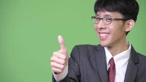 Young-happy-Asian-businessman-smiling-while-giving-thumbs-up