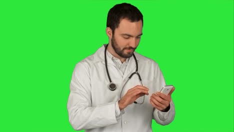 Medical-macho-médico,-enviar-un-mensaje-con-su-teléfono-celular-mientras-sonríen-y-de-pie-sobre-una-pantalla-verde,-Croma-Key