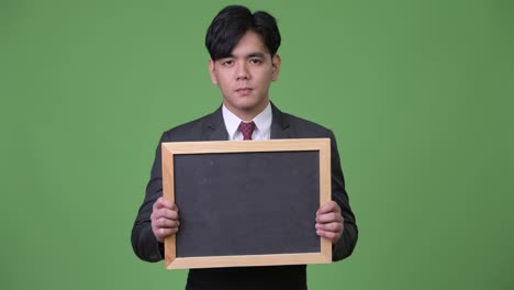 Young-handsome-Asian-businessman-showing-blackboard