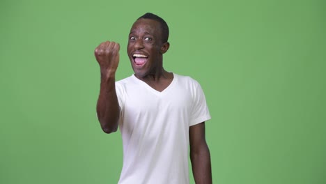 Young-happy-African-man-with-fist-raised-against-green-background