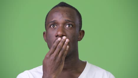 Young-African-man-looking-shocked-and-guilty-against-green-background