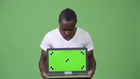 Young-African-man-looking-shocked-while-showing-laptop