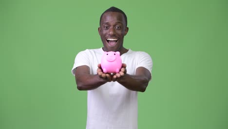 Young-African-man-holding-piggy-bank