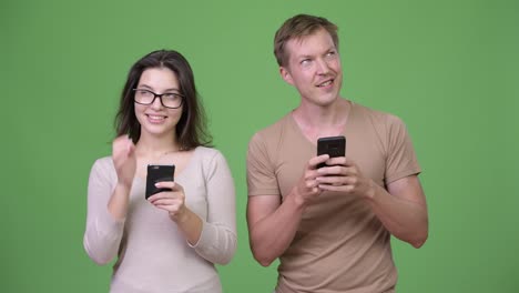 Young-happy-couple-using-phone-and-thinking-together