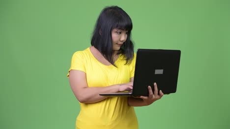 Schöne-asiatische-Frau-denken-während-mit-laptop