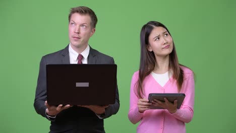 Junge-asiatische-Frau-und-junger-Geschäftsmann-mit-Laptop-und-digital-Tablette-zusammen