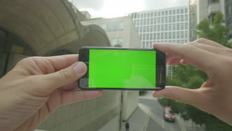 Perspectiva-personal-de-un-hombre-usando-un-smartphone-de-pantalla-verde-fuera-de-la-oficina