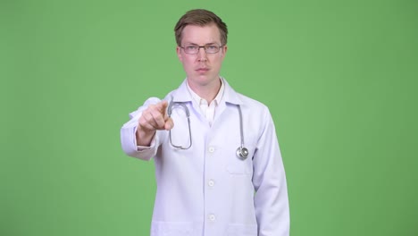 Portrait-Of-Young-Man-Doctor-Pointing-Finger