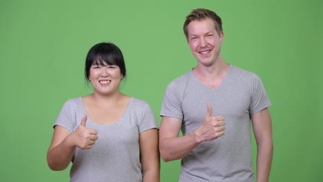 Young-multi-ethnic-couple-giving-thumbs-up-together