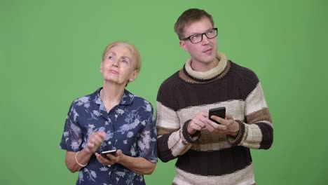 Happy-grandmother-and-grandson-using-phone-and-thinking-together