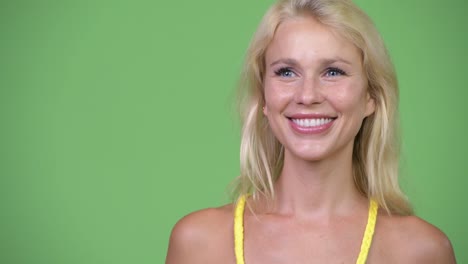 Junge-glücklich-schöne-blonde-Frau-vor-grünem-Hintergrund-denken