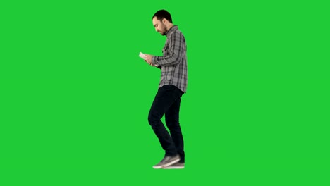 Confident-serious-man-walking-and-working-in-tablet-on-a-Green-Screen,-Chroma-Key