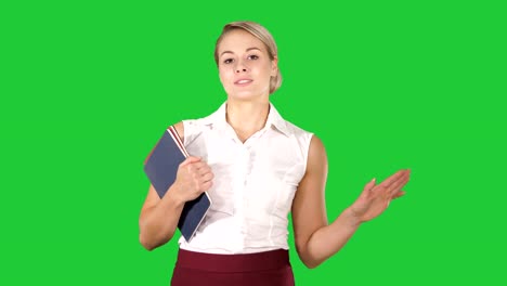 Beautiful-teacher-with-notebooks-explaining-something-to-camera-on-a-Green-Screen,-Chroma-Key