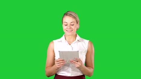 Beautiful-girl-holding-a-tablet-touch-pad-computer-gadget-swiping-pages-and-looking-in-camera-on-a-Green-Screen,-Chroma-Key