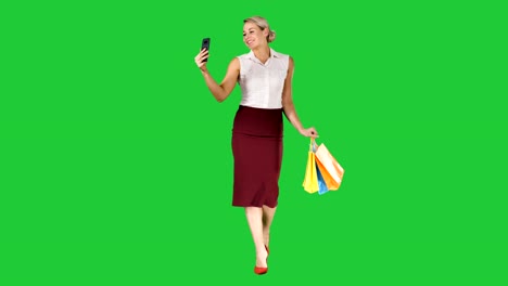 Сheerful-woman-with-shopping-bags-taking-selfie-on-a-Green-Screen,-Chroma-Key