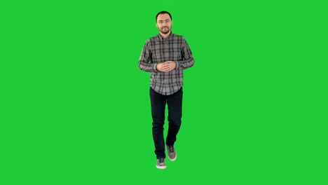 Young-confident-man-in-shirt-and-jeans-walking-towards-camera-and-pointing-to-the-sides-on-a-Green-Screen,-Chroma-Key