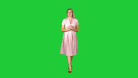 Glückliche-junge-Frau-inpink-Kleid-ist-Fuß-in-Richtung-Kamera-und-sprechen-auf-einem-Green-Screen,-Chroma-Key