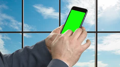 Man-with-smartphone-on-the-background-of-a-large-window.